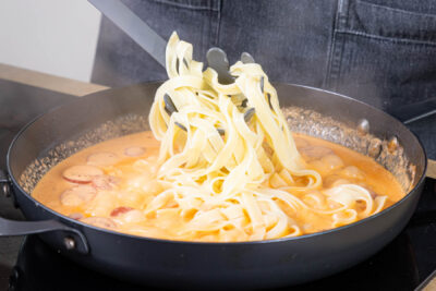 Tagliatelle in die Soße geben