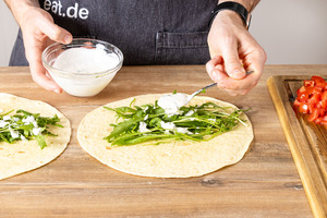 Knoblauchsoße über den Rucola geben