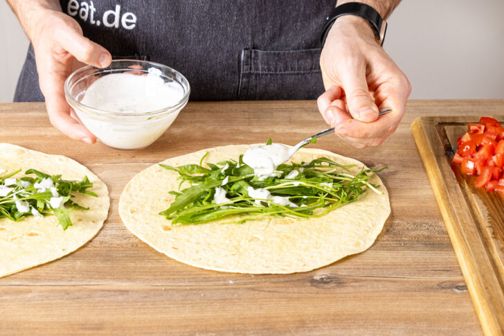 Knoblauchsoße über den Rucola geben