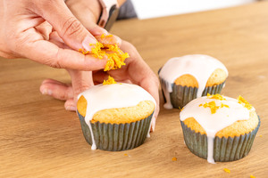 abgeriebene Orangen- und Zitronenschale auf den Guss der Muffins geben