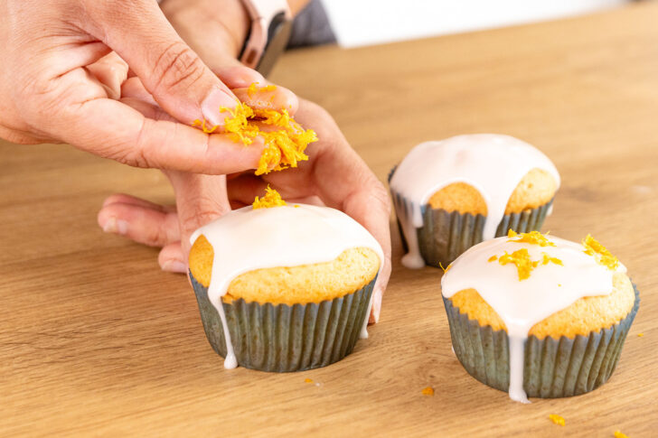 abgeriebene Orangen- und Zitronenschale auf den Guss der Muffins geben