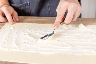 Blätterteig mit Frischkäse bestreichen