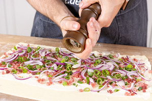 Blätterteigbelag mit Pfeffer würzen