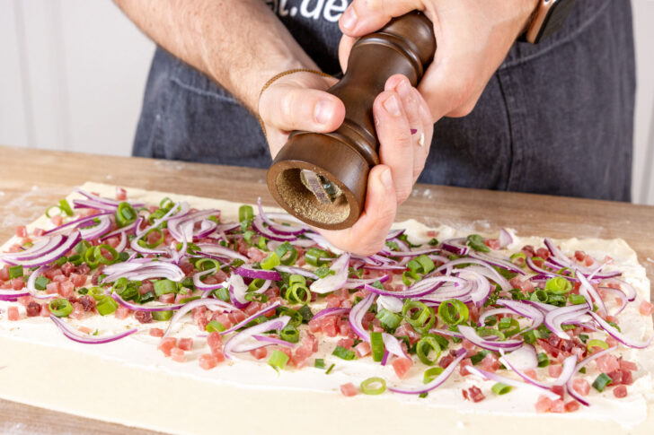 Blätterteigbelag mit Pfeffer würzen