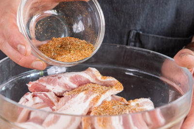 Die Gewürzmischung auf die Schweinebauchscheiben geben