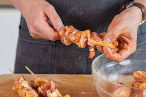 Den Schweinebauch auf die Holzspieße geben