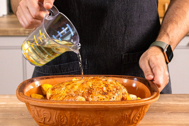 Weißwein zum Hähnchen im Römertopf mit Gemüse gießen