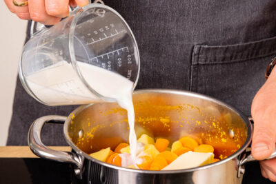 Butter und Milch zum gekochten Gemüse geben