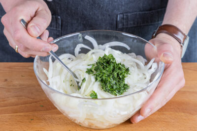 Das Dressing unter die noch warmen Zwiebeln mischen