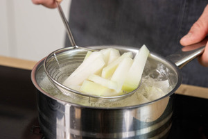 Kohlrabi mit einer Schaumkelle aus dem Wasser nehmen
