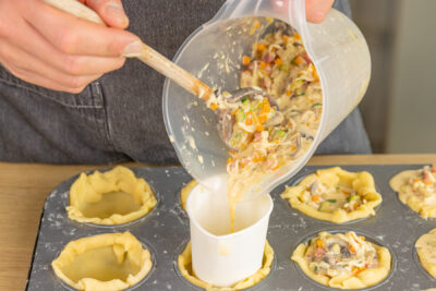 Quiche-Füllung in die Muffinförmchen geben