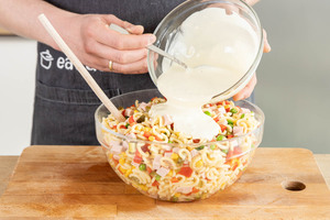 Nudelsalat mit dem Dressing vermengen