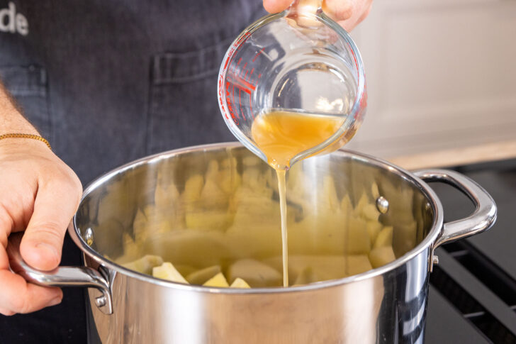 Apfelsaft zu den Apfelstücken im Topf gießen
