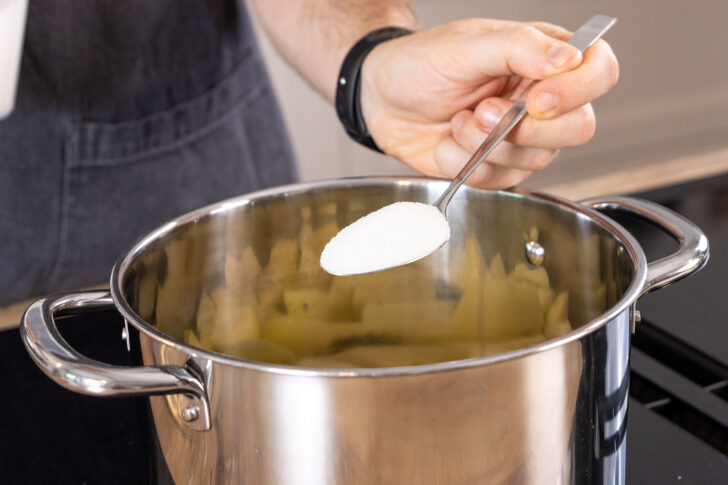 Zucker zu den Apfelstücken in den Topf geben