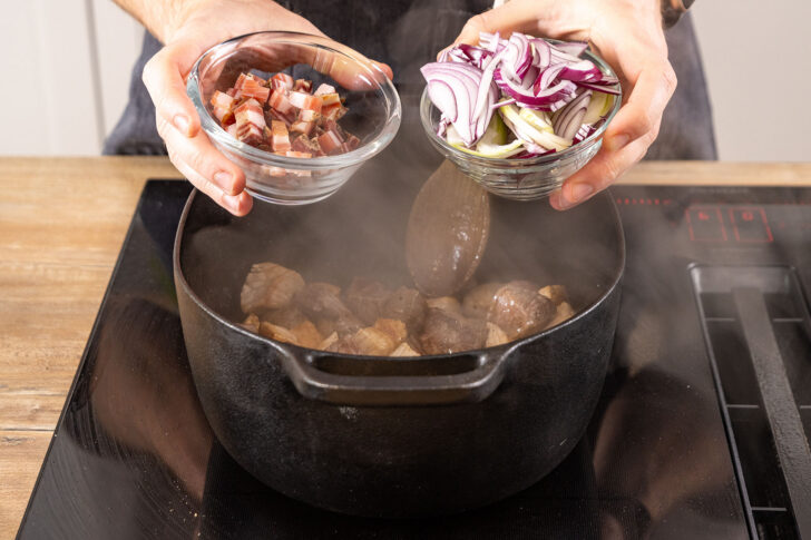 Speck und Zwiebel zum Fleisch in den Bräter geben