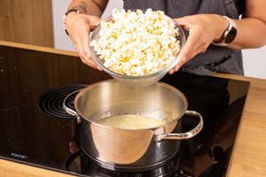 Popcorn zur geschmolzenen Zucker-Butter in den Topf geben