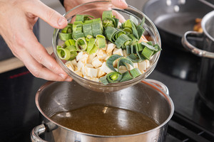Das Suppengrün in die Suppe geben