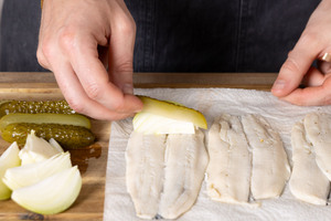 Zwiebel und saure Gurke auf den Heringen verteilen.