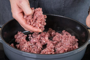 Lammhackfleisch in einem Bräter geben