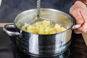 Kartoffeln mit einem Stampfer zerstampfen