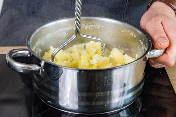Kartoffeln mit einem Stampfer zerstampfen
