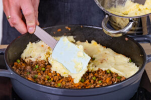 Kartoffelbrei auf der Hackfleischsauce verteilen