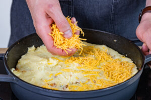 Cheddar auf dem Shepherd's Pie verteilen