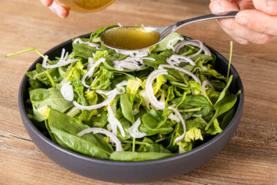 Dressing über den Spinatsalat geben