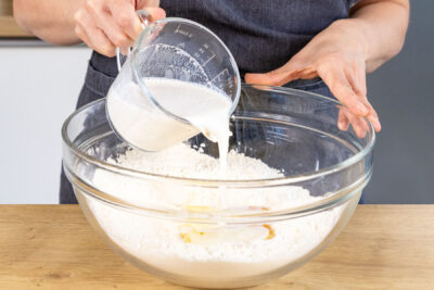 Hefe-Milch zum Mehl in die Schüssel gießen