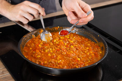 De Hackmasse mit Gewürzen und Tabasco abschmecken.