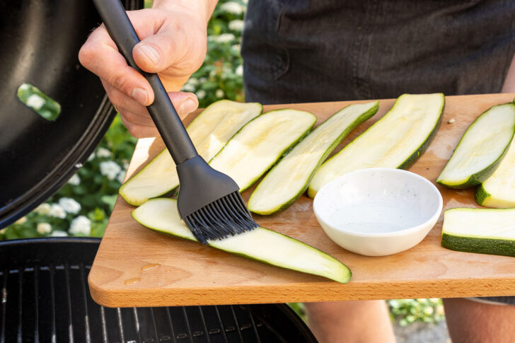 Zucchinischeiben mit Öl bestreichen