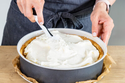 Schmandcreme auf der Apfel-Schmand-Torte verteilen