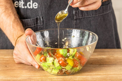 Honig zum Avocado-Tomaten-Salat geben
