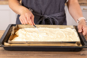 Schmandcreme auf dem Boden des Bienenkuchens verstreichen