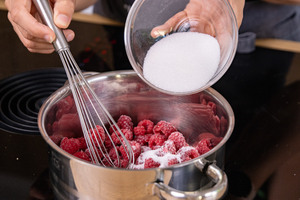 Zucker zu den Himbeeren geben