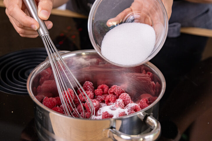 Zucker zu den Himbeeren geben