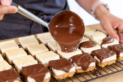 Schokoglasur über die Cheesecake-Bites gießen