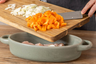 Paprika und Zwiebel in die Auflaufform geben
