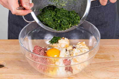 Spinat ausdrücken und zum Fleisch geben
