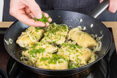Maultaschen mit Schnittlauch zu den Zwiebeln geben