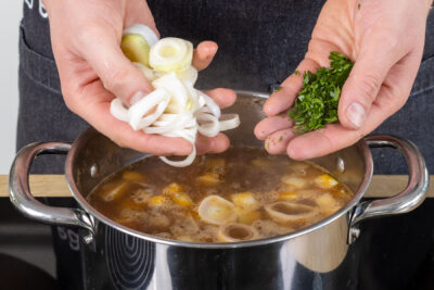 Lauch und Petersilie zum Kohlrabi-Eintopf geben