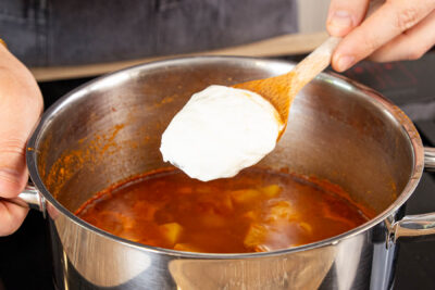 Schmand dazugeben und Gulasch abschmecken