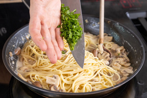 gehackte Petersilie zur Pasta mit frischen Champignons geben