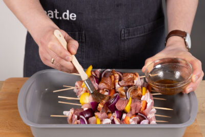 Die Spieße mit der Marinade bestreichen.