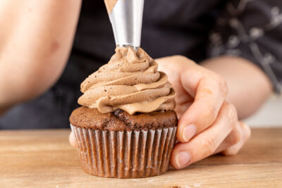 Buttercreme auf die Schoko-Cupcakes spritzen