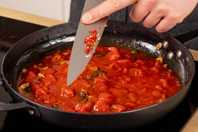 gehackte Tomaten und Chili in die Pfanne geben