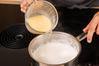 Vanillesauce in die köchelnde Milch geben