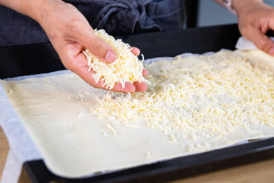 Blätterteig mit Käse bestreuen