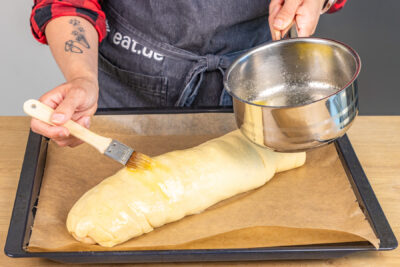 Apfelstrudel mit flüssiger Butter bestreichen