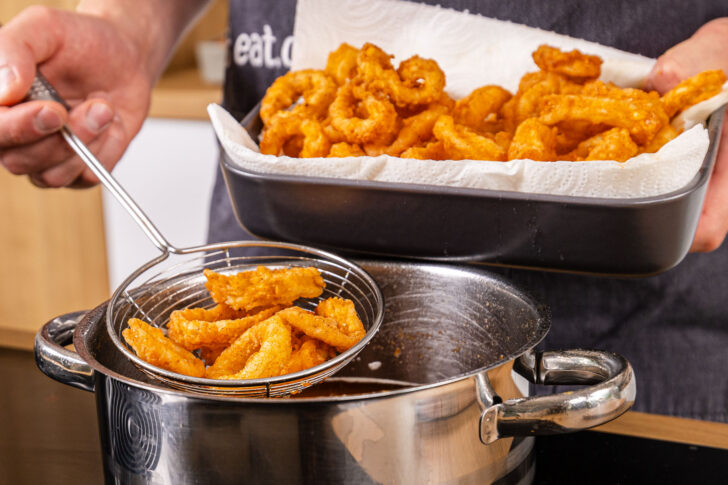 Frittierte Tintenfischringe aus dem Öl holen